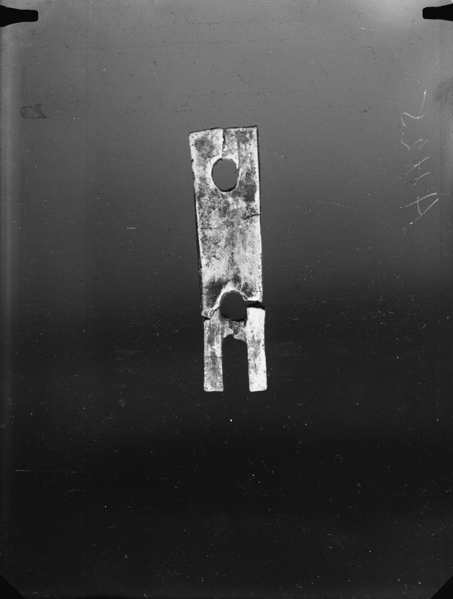 "4589 d. Litet gaffelformet redskap av ben med to huller. 5,4 cm. l., største bredde 1,4 cm. (Avb. SMÅ 1925, fig. 5.)"
Redskap av bein med uviss funksjon, i samsvar med beskrivelsen, tennene er knekte og ligger løse.  Stl: 54 mm, br: 12-14 mm, t: 3 mm. Hullene er ovale, st. tvm: 6 mm. Hullene er plassert midt på gjenstanden, det ene 6 mm fra øvre kant, det andre 15 mm fra nedre kant. Den ene tannen er bare 1,5 mm tykk i enden. Fragmentenes stl: 17, 18 og 39 mm.