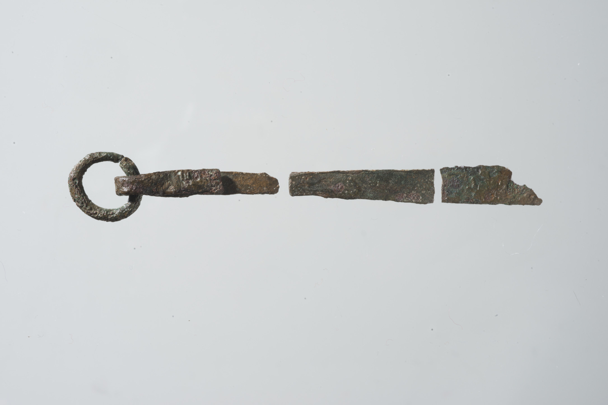 "8166 c. Pinsett av bronse i fire deler som VJG fig. 155. Overflaten er svært skadet, men har dog etter sporene å dømme vært ornert som typeeksemplaret. Største lengde: 9,1 cm." Ny beskrivelse etter revisjon: Pinsett av bronse i tre fragmenter, bestående av: (1) Pinsettringen med vedhengende bøyle med armer, knekte i forskjellig lengde. Ring diam: 13-15 mm, bøyle stl: 32 mm. Dekor av profilerte tverrstreker bevart på begge armer like under bøylen (sml. R164).  (2) To sammenpassende fragmenter av den andre armen, l: 20 og 29 mm, sammenlagt l: 49 mm, br: 5-7 mm.