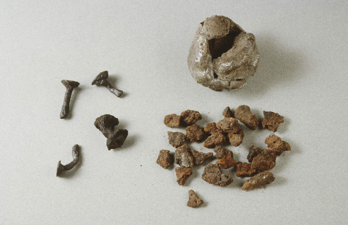 "2 nagler, l. 2,1 og 3 cm. 2 spikrer, l. 4,1 og 4,3 cm. 4 hoder, d. 1,2-1,3 cm. 28 hoder med stilk, l. 0,6-3,5 cm. 20 stilkdeler, l. 1,1-3,2 cm. 11 rør med stilk, l. 0,8-3 cm. 19 rør, l. 1,1-2,4 cm. Alle av jern." Åttifem fragmenter av nagler og spiker av jern i samsvar med beskrivelsen.