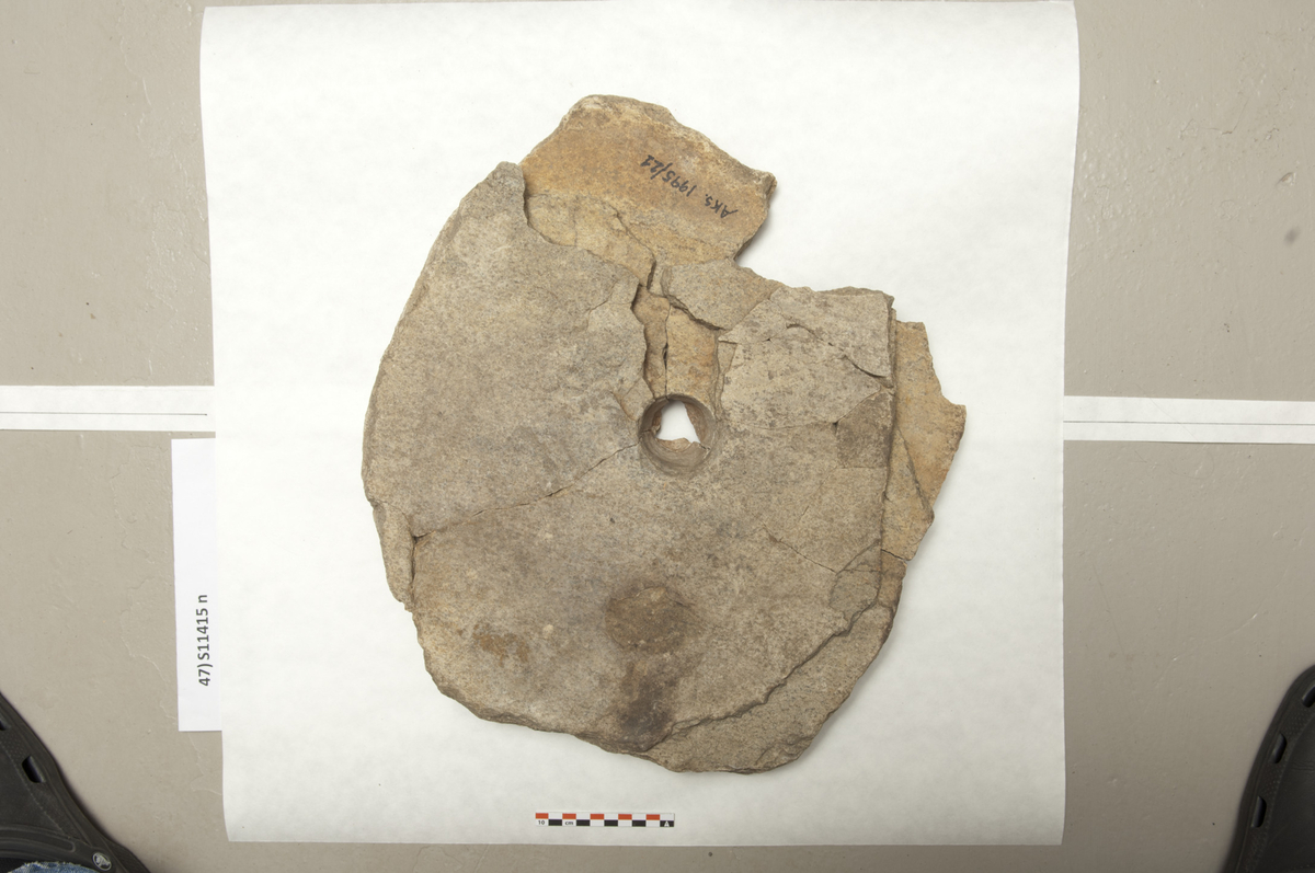 Et større fragment (limt sammen av minst seksten deler) av drejekvern med flat og lidt glattet overflate. Fragmentets form er rektangulær med avrundede kanter. I midten finnes ovalt midthul med diam. ca. 55 mm. St. m. 445 mm. (Fnr. 340)