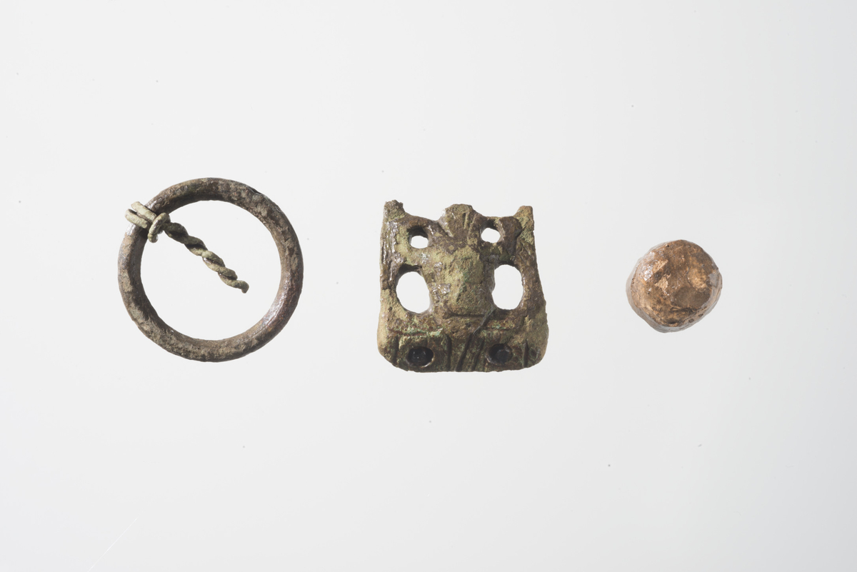 Ringspenne av kobberlegering lik Søvsø type 1.1 fig. 2 med st.d. 27 mm, og st.t. på ring: 0,35 cm. Ringspennen er glatt uten dekor. Nålen som skiller seg fra nålen på typefiguren, er laget av to kobbersnorer som er knyttet til spennen og tvunnet sammen til en nål. Det er ikke nålefeste på ringen slik at nålen kan flyttes rundt hele ringen. Nålen dateres generelt til middelalder.