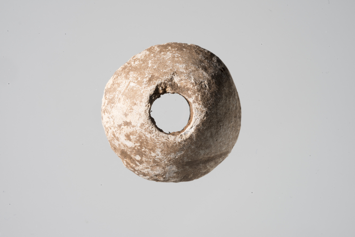 Spinnehjul av bly med rett basis, krum topp og krumme sideflater. Størst bredde ved basislinjen. Teinhullets diameter er på 7-8 mm. Et mulig dekorelement utgjør en forholdsvis bred fure som delvis omkranser hullet på hjulets underside/basis.