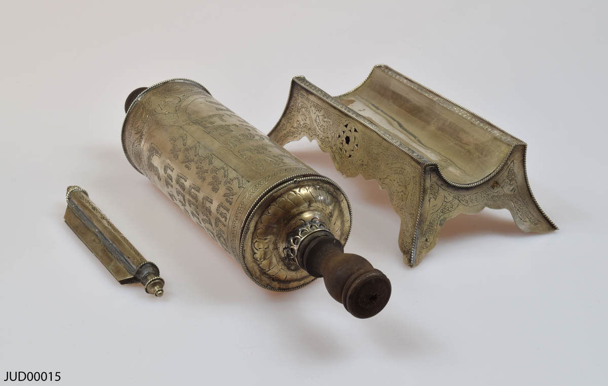 En tom silverrulle med trähandtag för Megillat Ester, med tilllhörande  stöd för rulle samt fäste för texten som båda är tillverkade av silver. Rikt dekorerad i form av gravyr, föreställande bland annat de tio budorden på hebreiska.