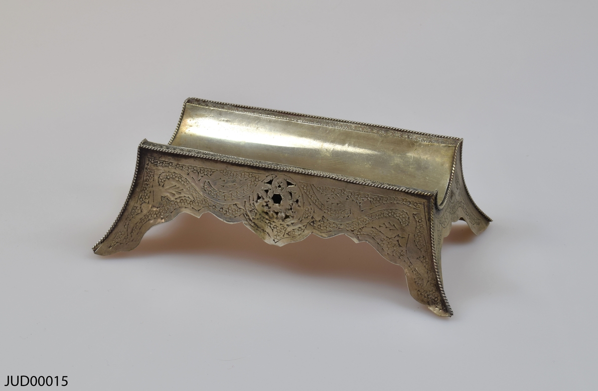 En tom silverrulle med trähandtag för Megillat Ester, med tilllhörande  stöd för rulle samt fäste för texten som båda är tillverkade av silver. Rikt dekorerad i form av gravyr, föreställande bland annat de tio budorden på hebreiska.