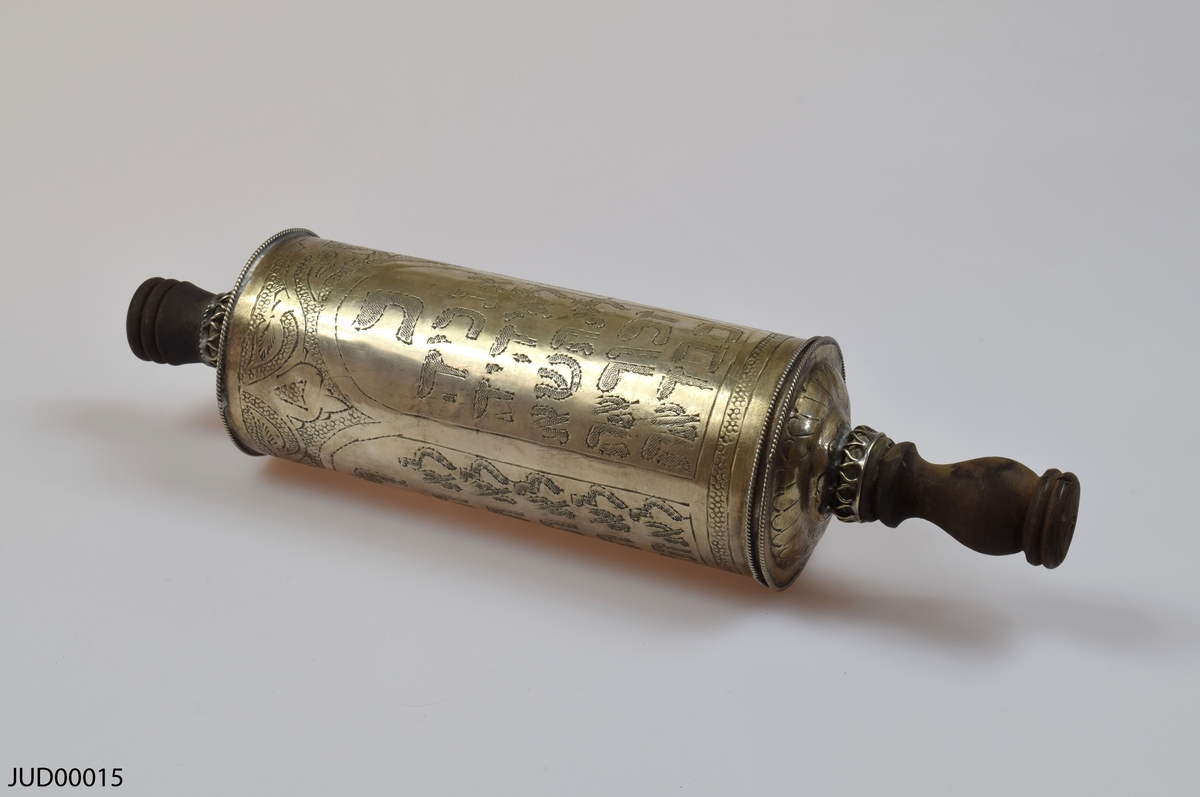 En tom silverrulle med trähandtag för Megillat Ester, med tilllhörande  stöd för rulle samt fäste för texten som båda är tillverkade av silver. Rikt dekorerad i form av gravyr, föreställande bland annat de tio budorden på hebreiska.