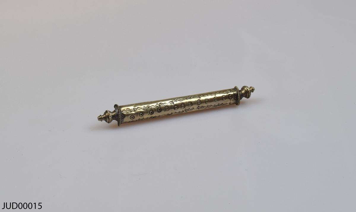 En tom silverrulle med trähandtag för Megillat Ester, med tilllhörande  stöd för rulle samt fäste för texten som båda är tillverkade av silver. Rikt dekorerad i form av gravyr, föreställande bland annat de tio budorden på hebreiska.