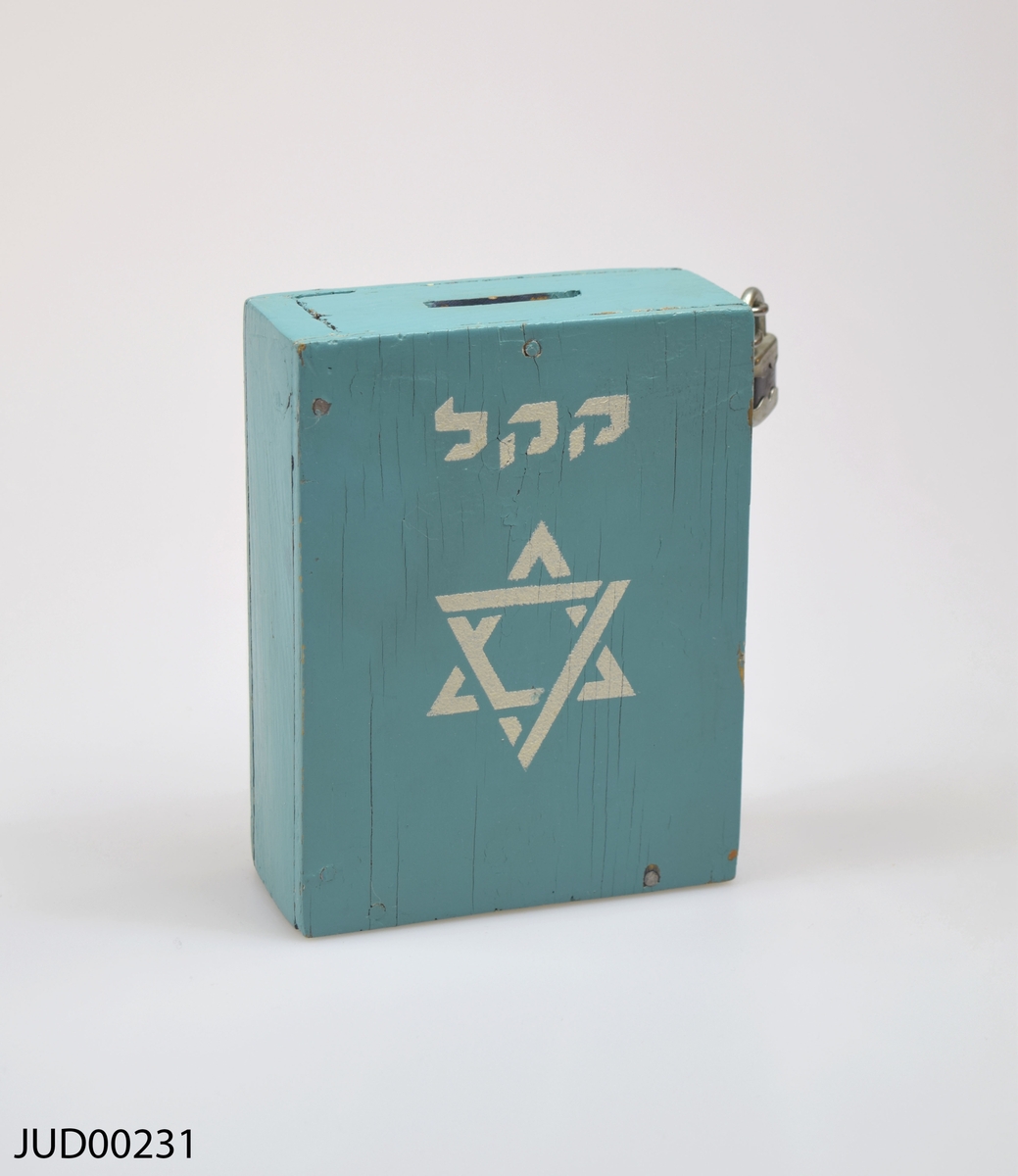 Insamlingsbössa, tillverkad av trä och sedan målad med turkos färg. Hänglås fastsatt på ena sidan.