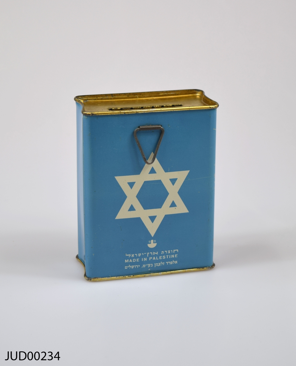 Insamlingsbössa, tillverkad av plåt och målad med turkos färg. Dekorerad med vit davidsstjärna samt vit hebreisk text.