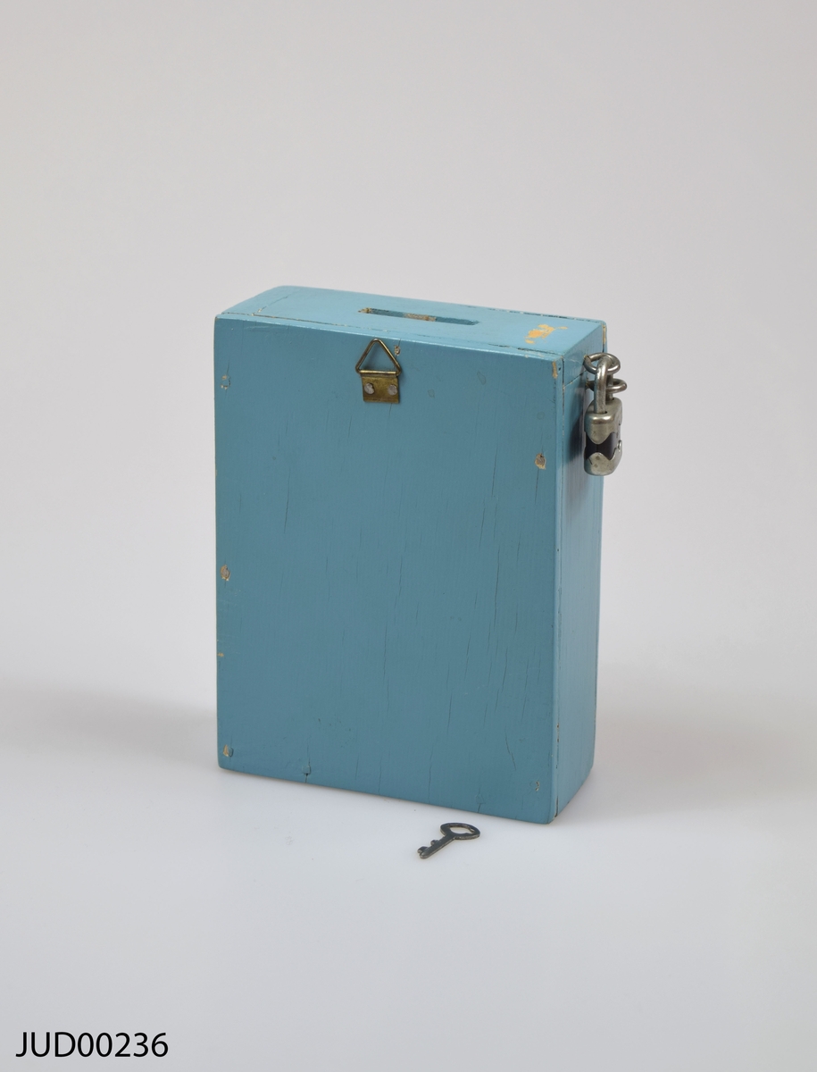 Insamlingsbössa, tillverkad av trä och målad med ljusblå färg. Dekorerad med en vit davidsstjärna samt vit hebreisk text.