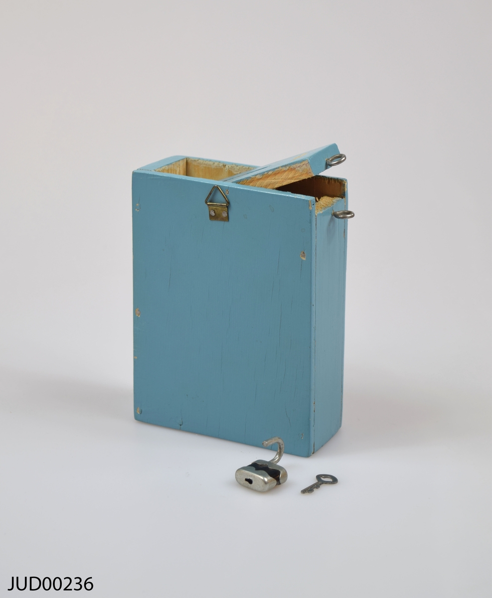 Insamlingsbössa, tillverkad av trä och målad med ljusblå färg. Dekorerad med en vit davidsstjärna samt vit hebreisk text.