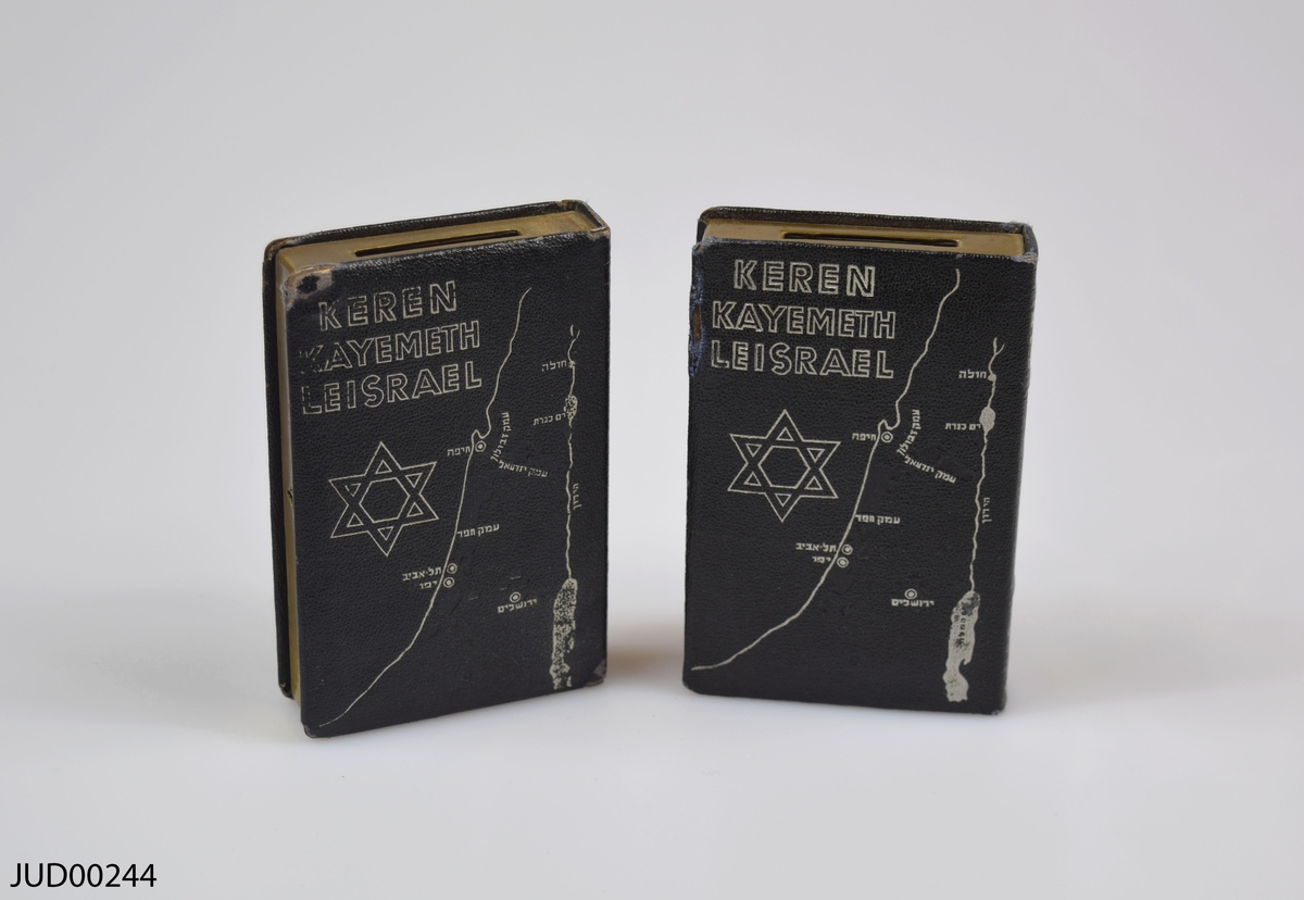 Två stycken insamlingsbössor utformade som böcker, tillverkade av mässing. Silvrig dekor i form av Davidsstjärna, karta över Israel samt hebreisk text. Även dekorerad med följande text:
Keren Kayemeth Leisrael
JNF Jerusalem