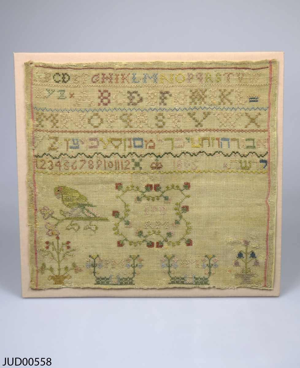 Märkduk med broderier. En blandning av broderade latinska och hebreiska bokstäver, siffror och  figurer.