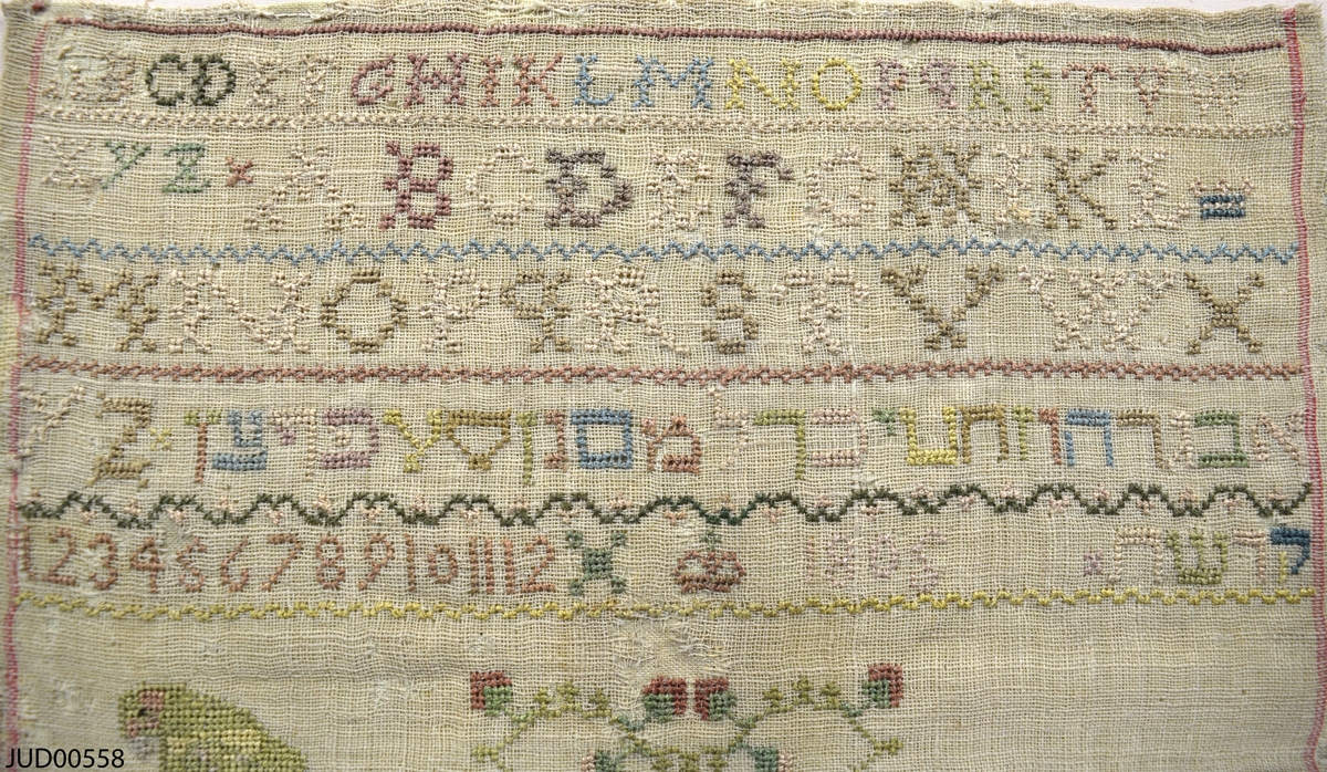 Märkduk med broderier. En blandning av broderade latinska och hebreiska bokstäver, siffror och  figurer.
