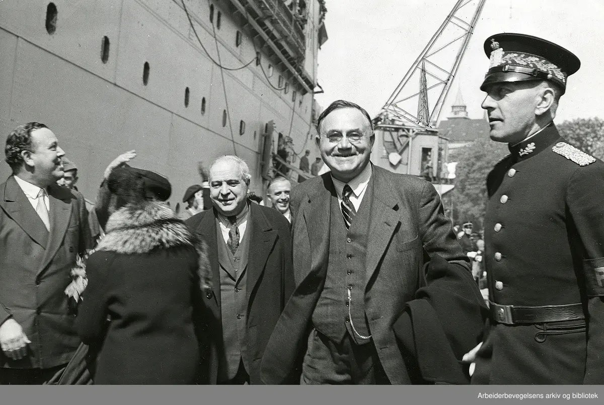 Regjeringen Nygaardsvolds hjemkomst 31. mai 1945..Fra v.: Trygve Lie, Albine Nygaardsvold (med ryggen til), C. J. Hambro, Nils Hjelmtveit ( i bakgrunnen) statsminister Johan Nygaardsvold. Til høyre politiinspektør, senere politimester, Sigurd Svein Skalmerud ved Oslo politikammer. .