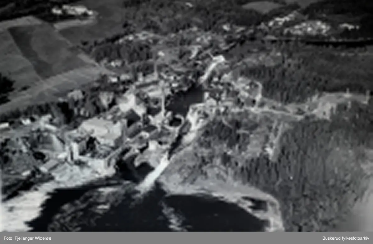 Flyfoto av Follum.
Hofsfos og Hofs Brug ligger bakenfor Follum Træsiberi på henholdsvis venstre og høyre side av elva.
