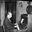 En okänd man sitter vid ett piano på Ribbagården.