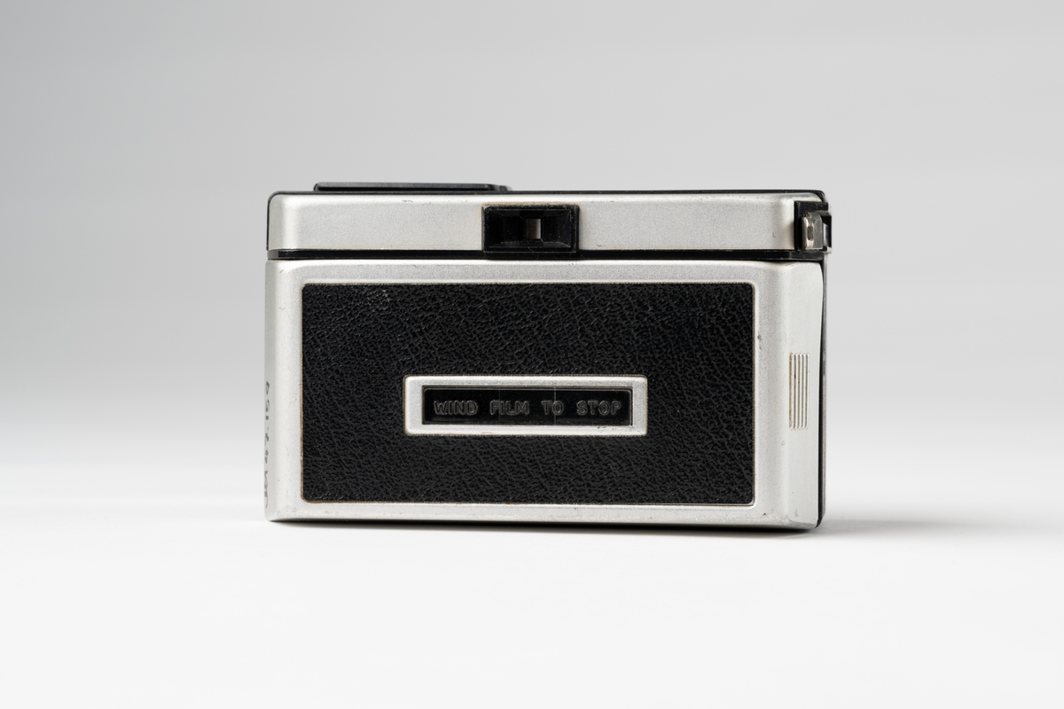 Kamera, Instamatic 100 av märket Kodak för filmkassetter. Av grå metall och svart konstläder. Öppning på baksidan, sikthål upptill i mitten fram och uttag för blixt på ovansidan.
