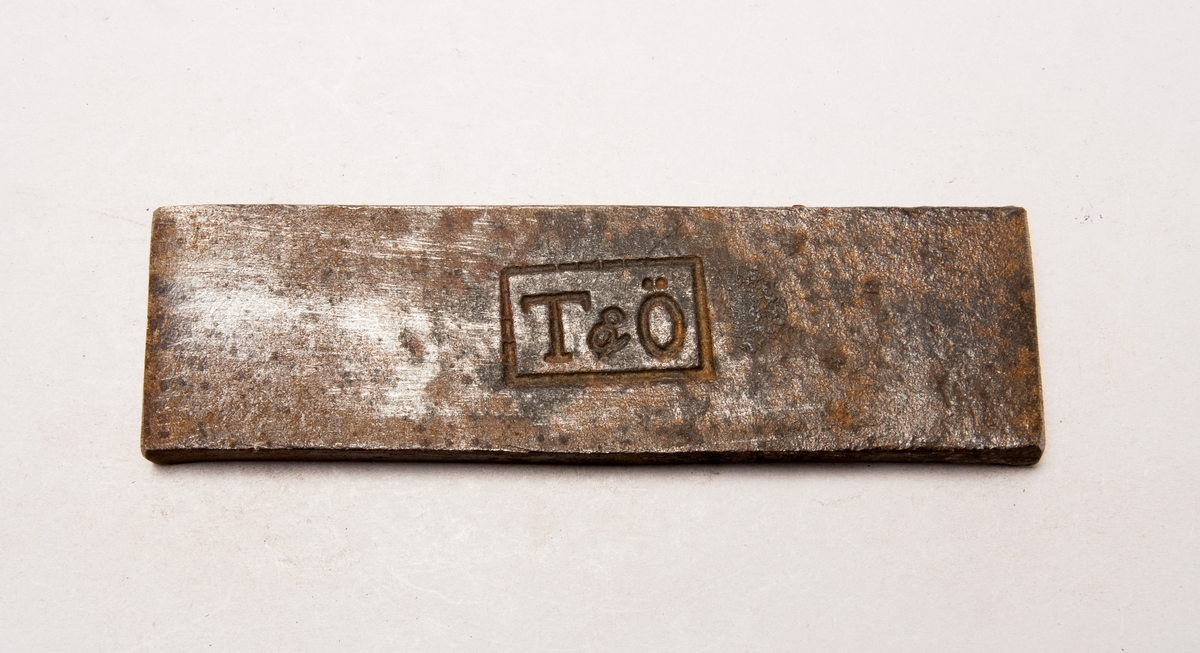 Järnstämpel från Elfkarleö. Stämpeln är ett stort "T" med ett stort "Ö" med "&" mellan dom.