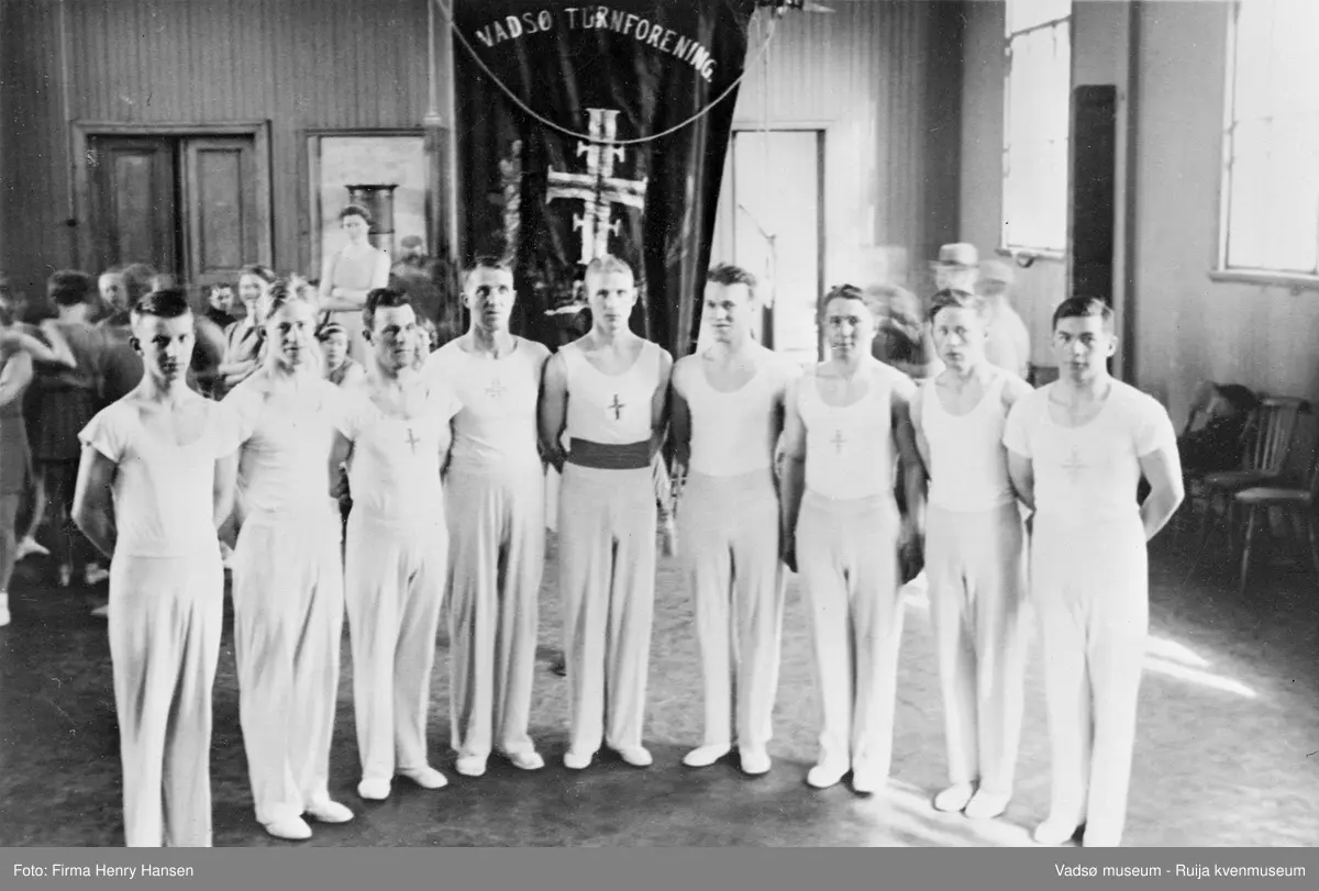 Vadsø 1938. Vadsø Turnforenings herreturngruppe samlet foran  VTF's fane i Vadsø folkeskoles gymnastikksal i forbindelse med et kretsturnstevne.
Fra venstre: Harry Hansen, Karl Hansen, Olav Brevik, Aksel Hansen, Karl Rasmussen, Georg Melsvik, Arne Brevik, Alf Hansen og Alf Rabbås.
Kilde; "Vadsø Turnforening gjennom 75 år 1895-1970" v/Niska, G. et.all 1970".