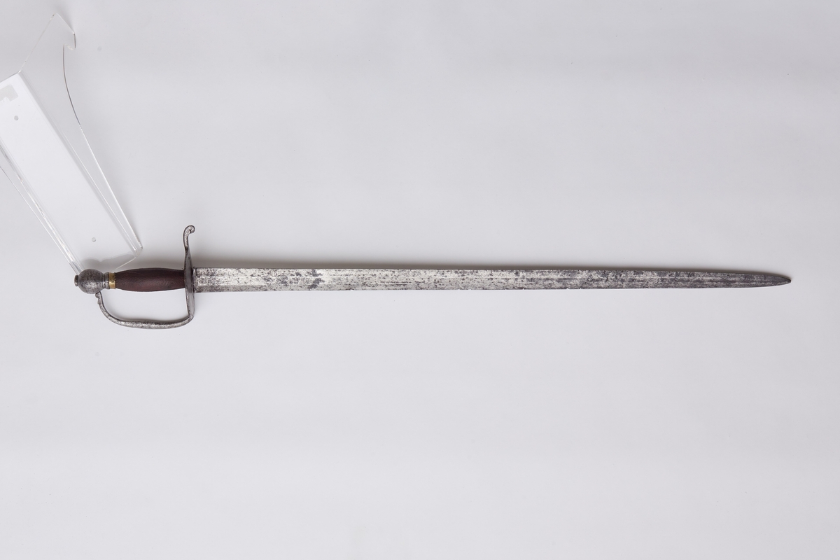 Tveegget sverd med flat klinge og brede egger. Parerplate, bøyle og knapp av jern. Kavle av tre med messingholker rundt endene. På klingen speilmonogram F 4 med krone over. På knappen H N0 5. solid parerplate som går over i en 3 cm lang stang med nedbøyd ende. Bøylen er en fortsettelse av platen og er svakt rundet og stukket inn i knappen. Eggformet knapp med spissen ned, knott på toppen der tangen er klinket. Kavlen har hatt surring av tvunnet messingtråd, rester av tråd sitter igjen under messingholkene. Klingens egg har huggsår.