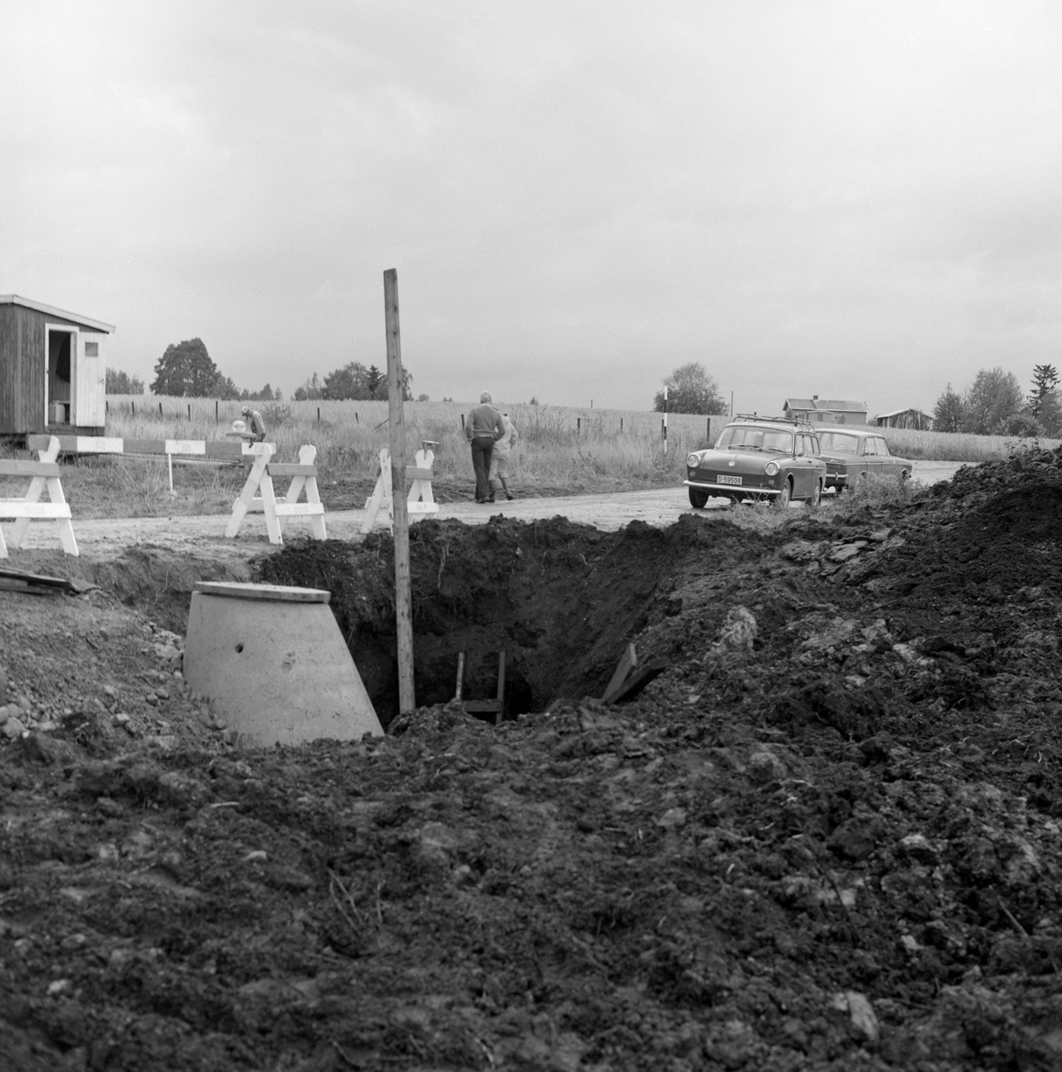 Nedgravd hull i bakken på et av jordene på garden Hov i Løten, der det høsten 1974 ble satt ned en kloakkum. Her ble det funnet et elggevir bemerkelsesverdig langt nede i jordlagene. En radiologisk analyse tydet på at geviret hadde ligget der i om lag 8 500 år. Dermed ble det interessant å forteta en naturhistorisk undersøkelse i jordsmonnet der geviret hadde ligget. Dette var ikke første gang det ble gjort en slik undersøkelse på Hov. Også i 1965 ble det funnet et gevir som viste seg å være cirka 8 000 år gammelt. Funnet utløste oppfølgingsundersøkelser med pollenanalytisk og limnologisk ekspertise fra Universitetet i Oslo. Det var Kari og Gunnar Henningsmoen som den 7. og 8. september 1974 kom til Løten for å ta jordprøver med sikte på å kartlegge biologiske forhold på funnstedet gjennom årtusener.

Se fanen «Opplysninger» og litteraturreferansene til dette fotografiet.