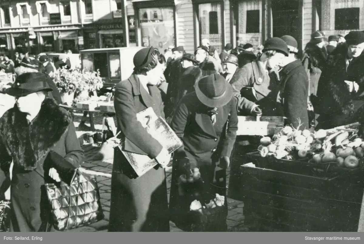 Grønnsakshandel på Torget i Stavanger sentrum. Kvinner som handler neper og blomster.