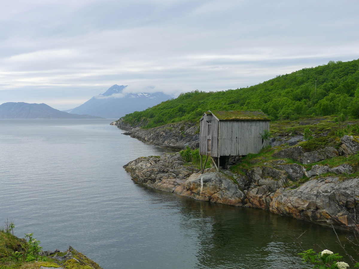 Brygge i to etasjer, stavkonstruksjon i første etasje med laftet overetasje. Tak tekket med plast og torv. Original kledning, dør og vindu. Vestveggen er skiftet. 