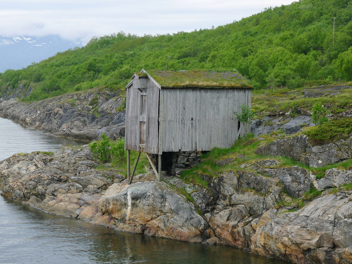 Brygge i to etasjer, stavkonstruksjon i første etasje med laftet overetasje. Tak tekket med plast og torv. Original kledning, dør og vindu. Vestveggen er skiftet. 