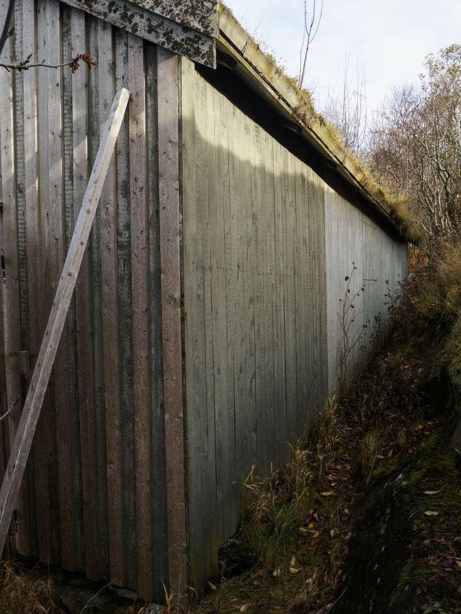 Naustet ligger inneklemt i en naturlig åpning i landskapet som går fra sjøen og opp på land. Bygningen har torvtak og stående panel. Dør og vindu i bakkant og stor port i framkant. For oppbevaring av båter.