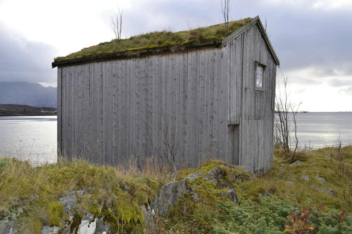 Brygge i to etasjer, stavkonstruksjon i første etasje med laftet overetasje. Tak tekket med plast og torv. Original kledning, dør og vindu. Vestveggen er skiftet. 
