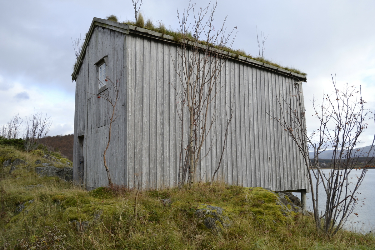 Brygge i to etasjer, stavkonstruksjon i første etasje med laftet overetasje. Tak tekket med plast og torv. Original kledning, dør og vindu. Vestveggen er skiftet. 