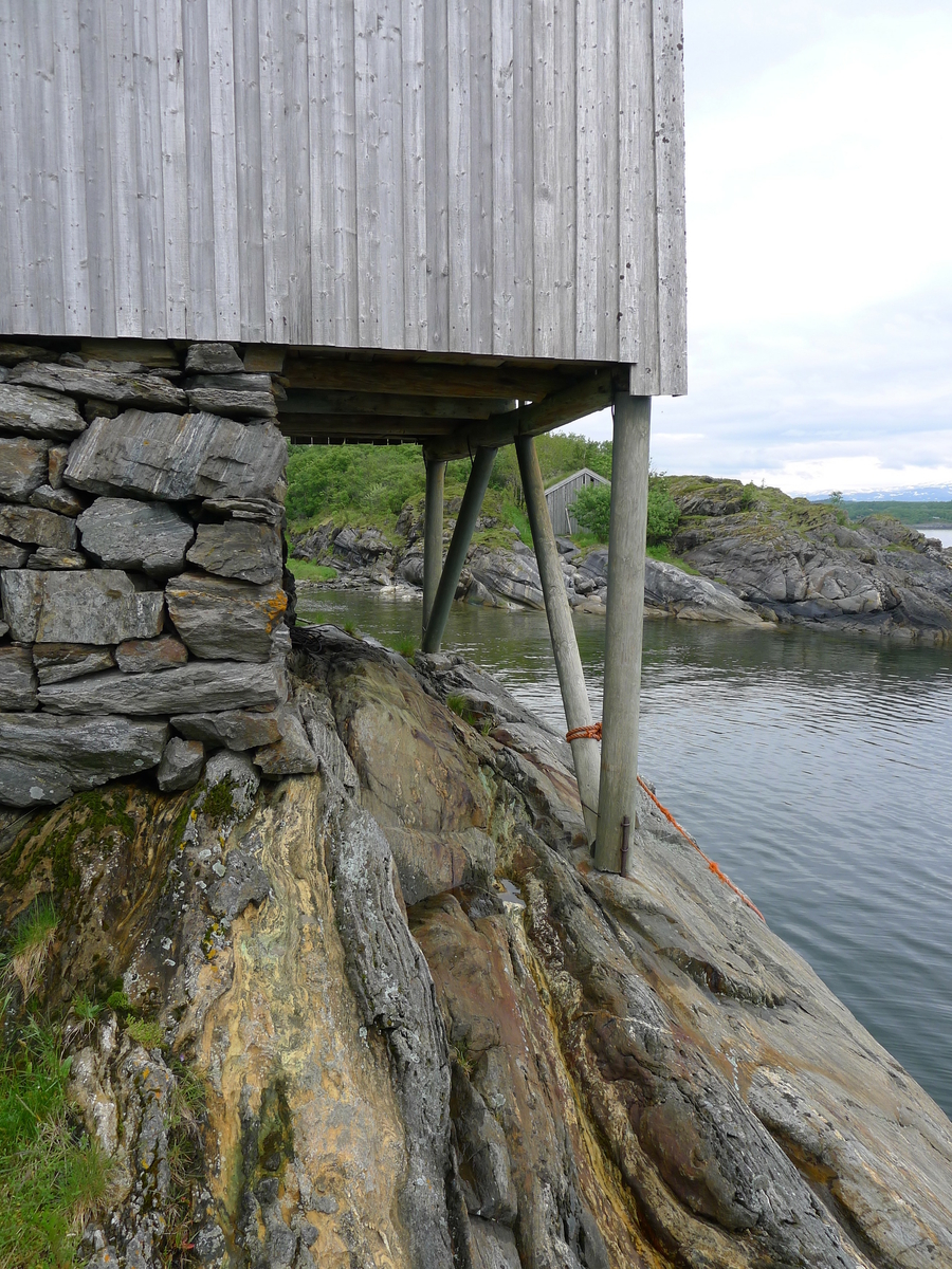 Brygge i to etasjer, stavkonstruksjon i første etasje med laftet overetasje. Tak tekket med plast og torv. Original kledning, dør og vindu. Vestveggen er skiftet. 