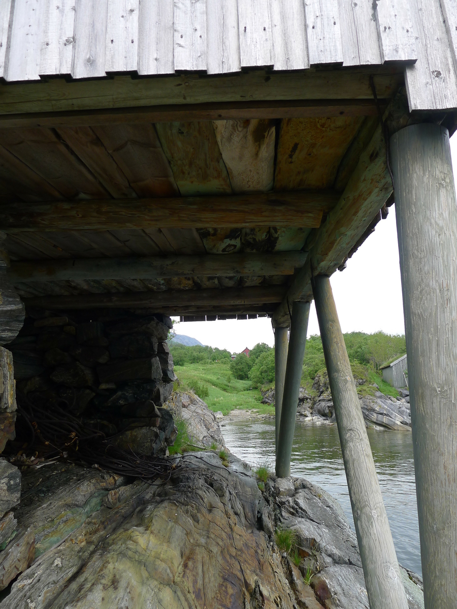 Brygge i to etasjer, stavkonstruksjon i første etasje med laftet overetasje. Tak tekket med plast og torv. Original kledning, dør og vindu. Vestveggen er skiftet. 