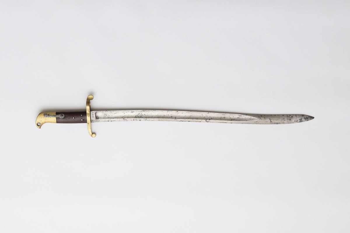 Sabelbajonett med jatangformet klinge, hulslipt, med tveegget spiss. Parerstang av messing, skjeftet av tre med en øvre del av messing. Parerstangens bakre arm danner en ring med diameter 23mm. Skjeftets øvre messingdel har spor for pipens bajonettklakk, låsingen skjer ved fjær og knapp av stål.