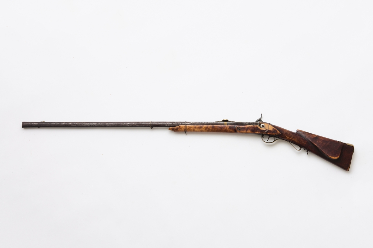 Glattløpet gevær med kassepipe og perkusjonslås. Skjeftet av bjørk, forskjeftet avbrukket 67 cm fra munningen, kolbekappe av messing, kolben har kinntre, bøyle og bøylebeslag av messing, geværet har hatt to stoppskiver istedenfor sideblikk, ved bakre låsskrue er endel treverk borte og erstattet med en tykk aluminiumsskive, forsikringer på hanen, pipens kammerende er firkantet, oppå er her prikket inn O T samt gravert I B ? S  ,langs begge kanter en fure, der pipen blir åttekantet er innslått enkel dekor, sikte av messing med V-formet skur og mange profiler festet med messingbånd rundt pipen.

Pipen er svampet, dvs at den er tykkest ved munningen.
Tydelig smedmerker på pipa.
