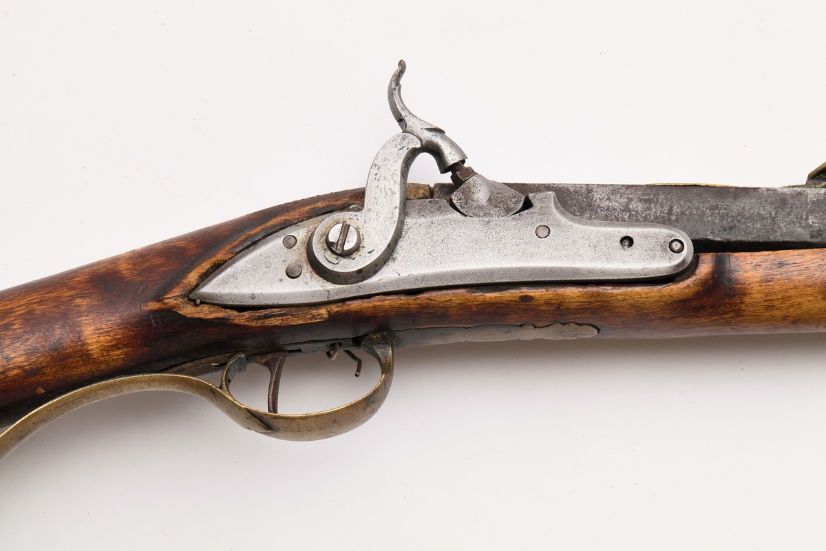 Glattløpet gevær med kassepipe og perkusjonslås. Skjeftet av bjørk, forskjeftet avbrukket 67 cm fra munningen, kolbekappe av messing, kolben har kinntre, bøyle og bøylebeslag av messing, geværet har hatt to stoppskiver istedenfor sideblikk, ved bakre låsskrue er endel treverk borte og erstattet med en tykk aluminiumsskive, forsikringer på hanen, pipens kammerende er firkantet, oppå er her prikket inn O T samt gravert I B ? S  ,langs begge kanter en fure, der pipen blir åttekantet er innslått enkel dekor, sikte av messing med V-formet skur og mange profiler festet med messingbånd rundt pipen.

Pipen er svampet, dvs at den er tykkest ved munningen.
Tydelig smedmerker på pipa.