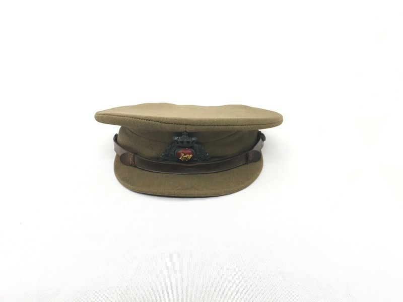 Brun uniformshatt med skygge og luemerke med ei gylden norsk løve på raud botn. Denne er omkransa av eikelauv med ei krune på toppen. Brunt lærband er festa til hatten med to gyldne knappar.