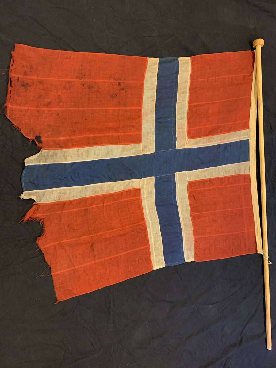 Det norske flagget med splitt.  Flagget er så slitt at splitten er nesten usynleg.
