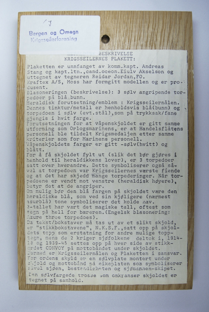 Ein plakett forma som eit skjold med tre torpedoar som illustrasjon.