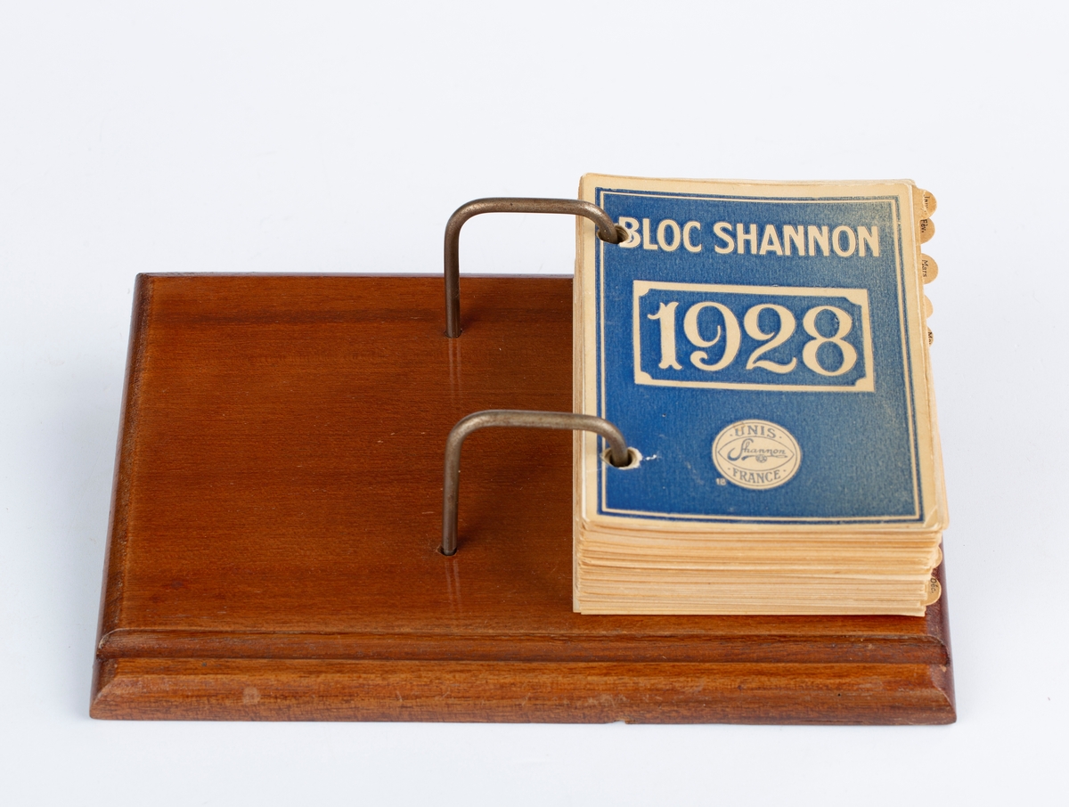 Bordkalender 1928, treplate, metallstenger, hvit kalenderblokk, papirark. Rektangulær. Notert i av RA. Med månedsskiller i brun papp. Mrk: Bloc Shannon 1928. Unis Shannon France. Siste notat 11. juni 1928.