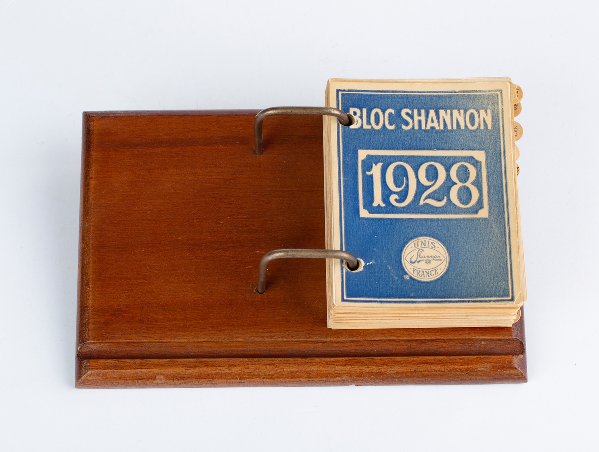 Bordkalender 1928, treplate, metallstenger, hvit kalenderblokk, papirark. Rektangulær. Notert i av RA. Med månedsskiller i brun papp. Mrk: Bloc Shannon 1928. Unis Shannon France. Siste notat 11. juni 1928.