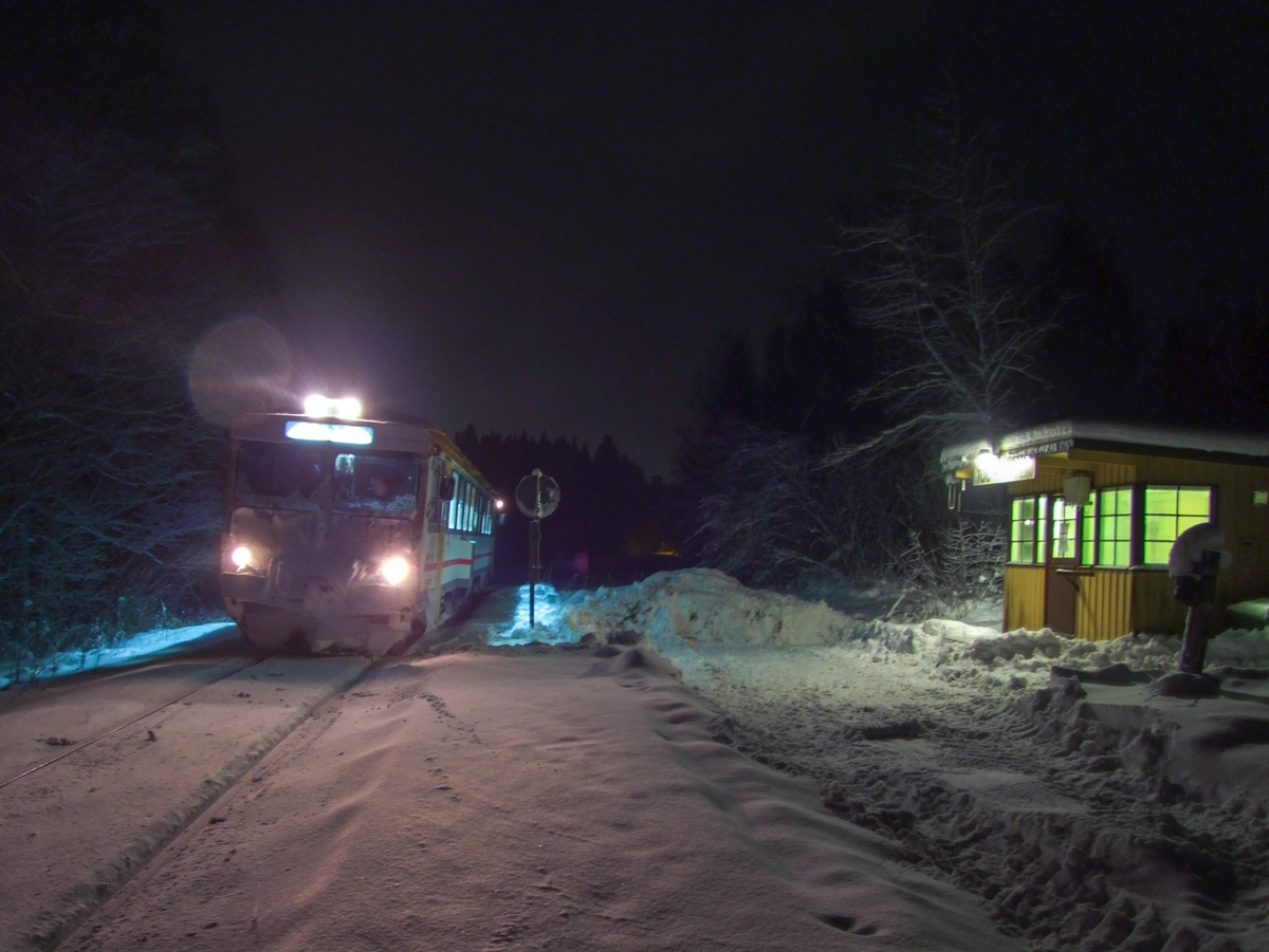 Hållplatskur från Tjunnaryd. Målad i ljusgul kulör med ljusgrå dörr, dörrfoder och fönsterfoder. Spröjsade fönster utmed hela framsidan, även på dörren, och delvis på sidorna.