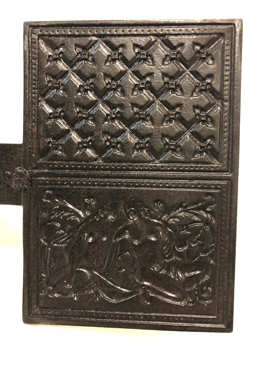 Langskaftet gorojern til bruk over åpen varme. Den ene siden er preget med Adam og Eva som motiv.