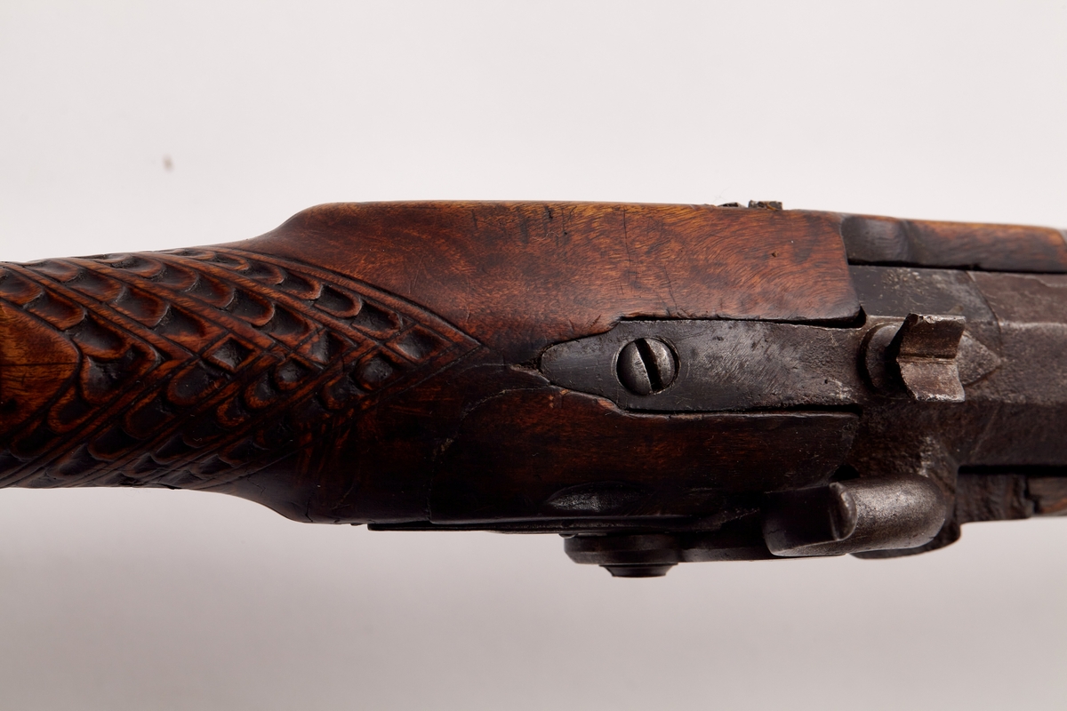 Gevær, glattløpet. Geværet har perkusjonslås, åttekantet pipe til 30,7 cm fra kammerenden, resten rund. Rikt utskåret skjefte, på låsblikket; S. Richards, og blomsterdekor bakerst. Geværet har kappe av messing med hæl og tå. Kolbehalsen er rikt skåret med striper og buer, og går rundt kolben over i en hund med framstrakt høyre ben og hengende ører. Fra spissrørkenet har forskjeftet profiler langsmed. Midtrørken mangler, det forreste er loddet til pipen. Under på pipens kammerende er innslått V. Påloddet sikteskur bakerst på pipen. Halvmåneformet 22 m. lang messingkorn med forreste ender 60 mm fra munningen. Låset har rik bladdekor på studdelen. Hanekroppen er S-formet og flat, hanemulen rund, hanefløyen glatt, med en liten bakoverbøy øverst. Lett jaktgevær.