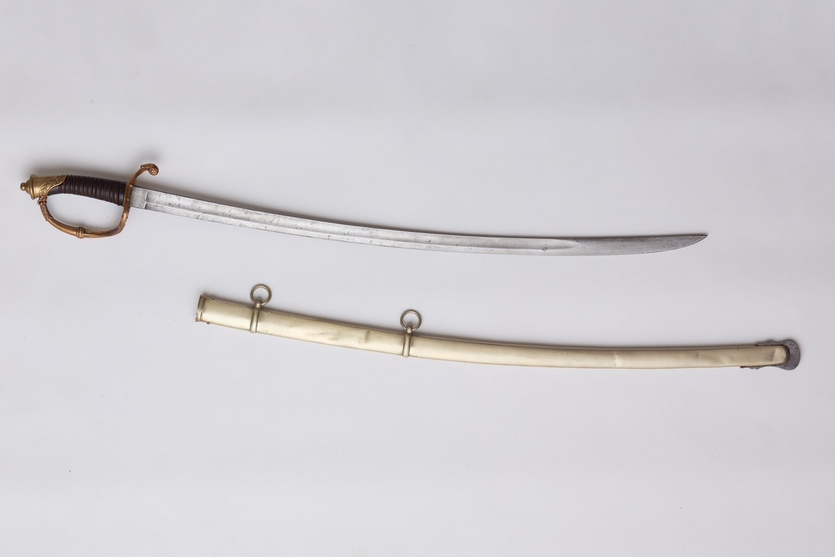 Sabel a): Klingen hulslipt til 17,5 cm fra spissen. Ryggen er tynnslipt fra spissen og 17 cm. oppover. Grepets plate, bøyle og knapp er støpt av messing. Kavlen er av presset horn med rifler hvori metallbånd. Dekorert.
