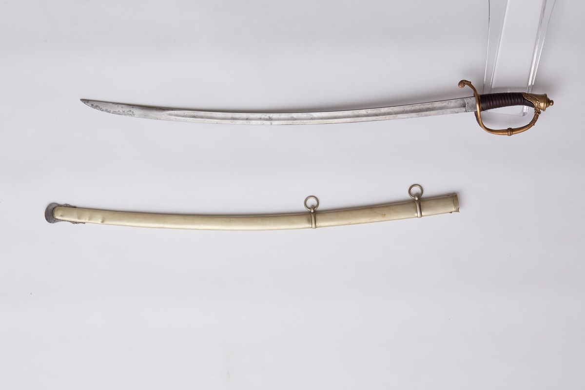 Sabel a): Klingen hulslipt til 17,5 cm fra spissen. Ryggen er tynnslipt fra spissen og 17 cm. oppover. Grepets plate, bøyle og knapp er støpt av messing. Kavlen er av presset horn med rifler hvori metallbånd. Dekorert.