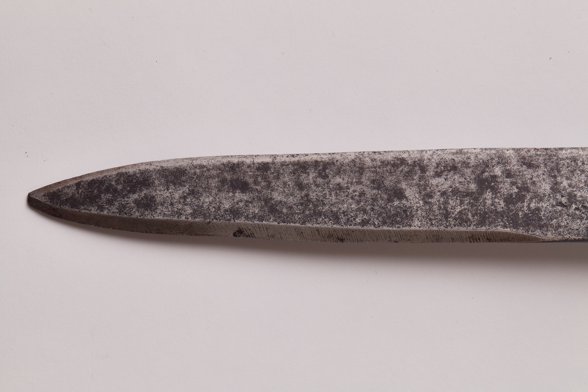 Sabel a): Klingen hulslipt til 17,5 cm fra spissen. Ryggen er tynnslipt fra spissen og 17 cm. oppover. Grepets plate, bøyle og knapp er støpt av messing. Kavlen er av presset horn med rifler hvori metallbånd. Dekorert.