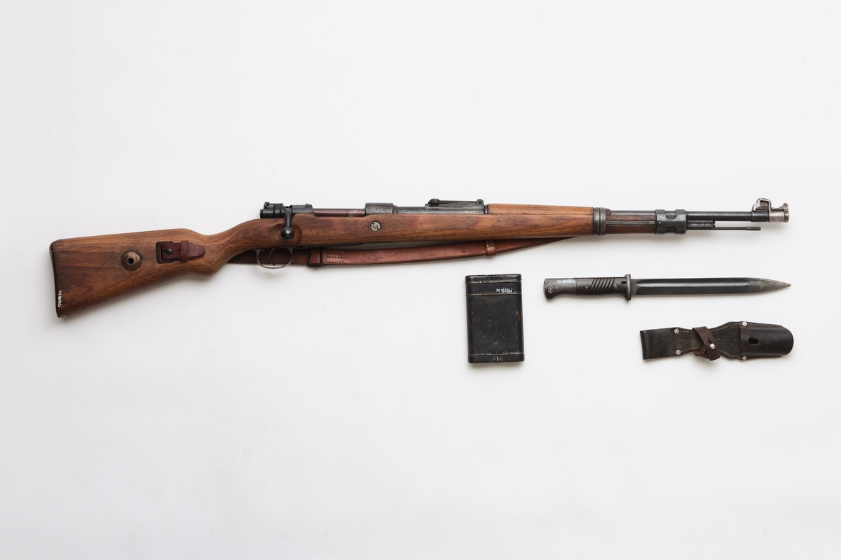 Mauser (a), bajonett (b) slire (c) og pussesett (d). En original og komplett Mauser kaliber 7.92, som var det vanligste våpenet brukt av den tyske armeen under 2. verdenskrig. I tillegg følger det med pussesett og bajonett med belteslire, men det mangler balg.