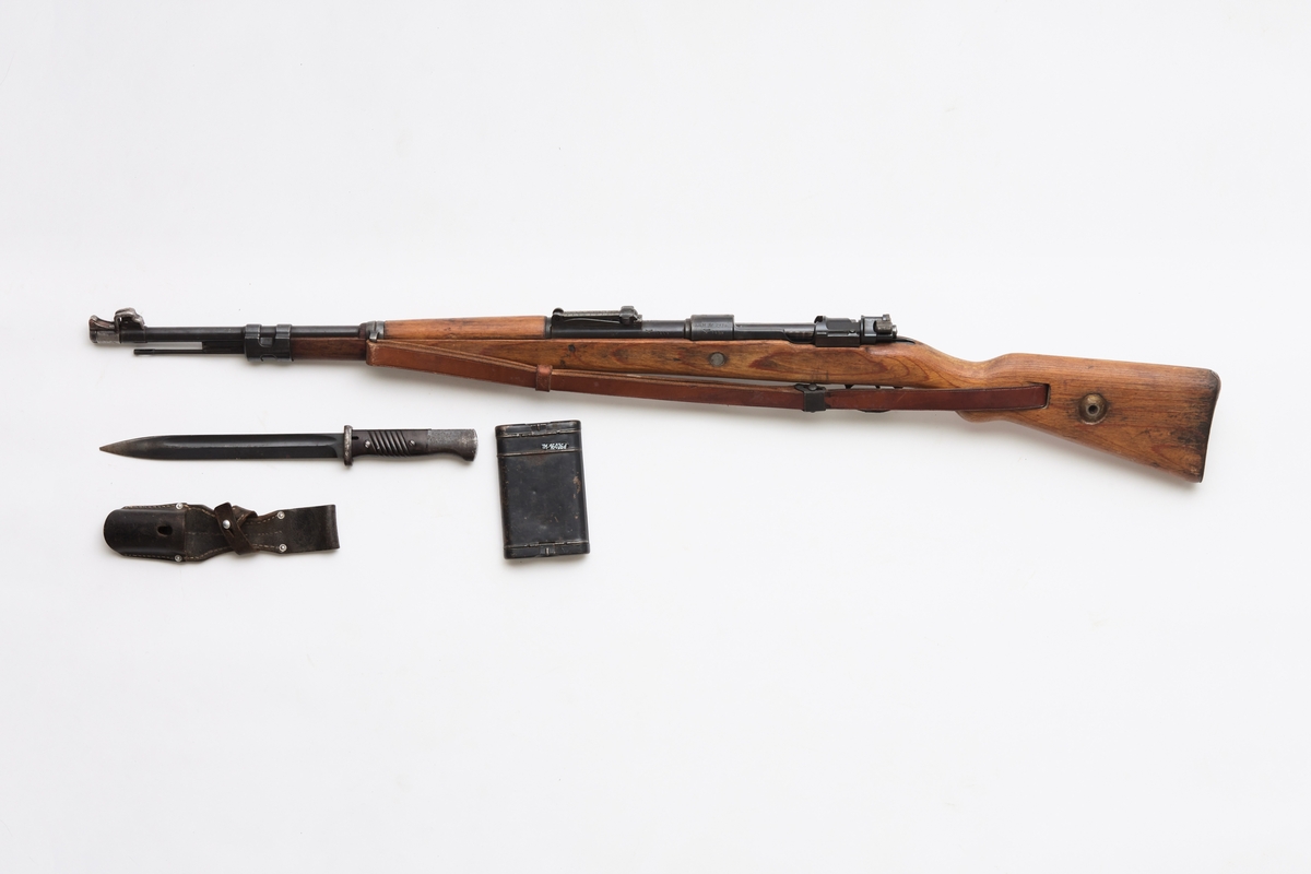 Mauser (a), bajonett (b) slire (c) og pussesett (d). En original og komplett Mauser kaliber 7.92, som var det vanligste våpenet brukt av den tyske armeen under 2. verdenskrig. I tillegg følger det med pussesett og bajonett med belteslire, men det mangler balg.