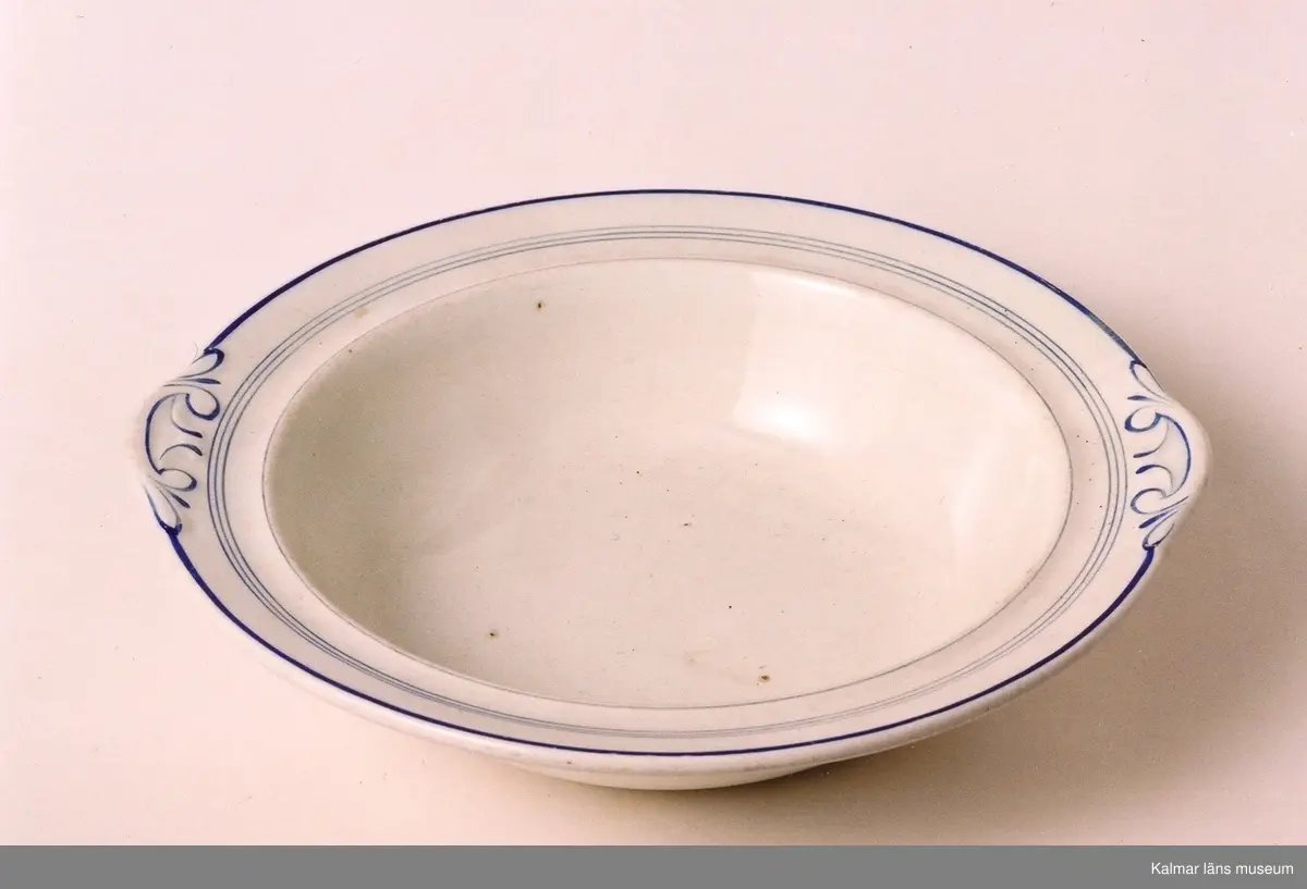 KLM 39615:1-2. Tallrikar, djupa, 2 stycken. Diam 22,5 cm, största diam vid dekor 23,6 cm, H 5 cm. Vitt porslin med blå dekorränder, dekor på brättet som förtydligar karaktären av greppen. Stämpel: inpressad: JL Rörstrand AD 9 z13.